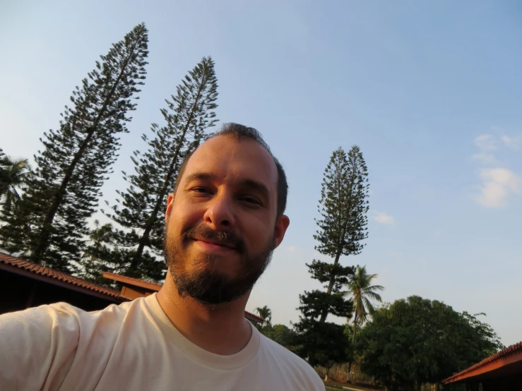 a man smiles at the camera under trees