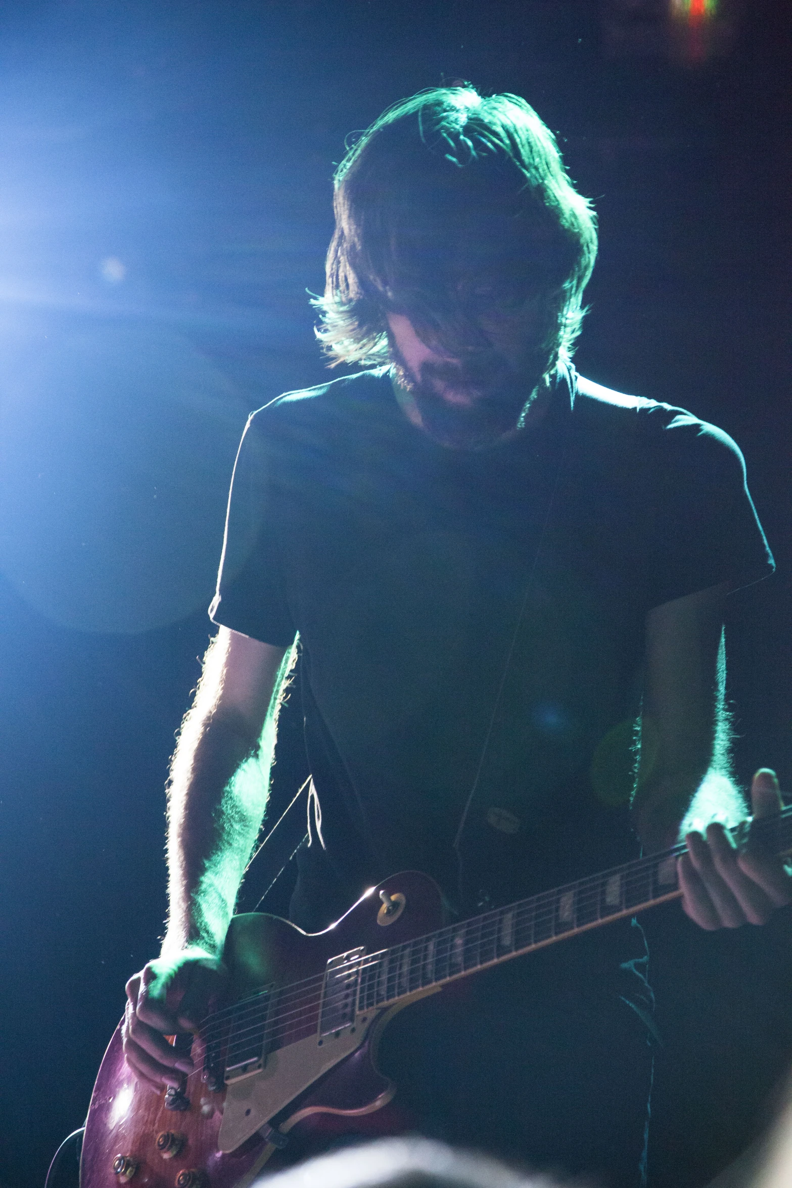 a man plays an electric guitar in a dark room