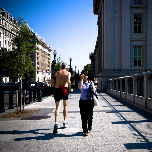 two men are walking down the sidewalk in a busy urban area