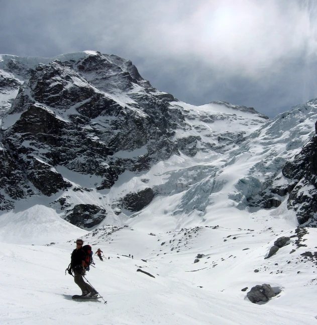 man with ski gear walking through snow covered mountains