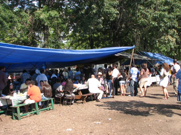a tent covered in tables and people standing around