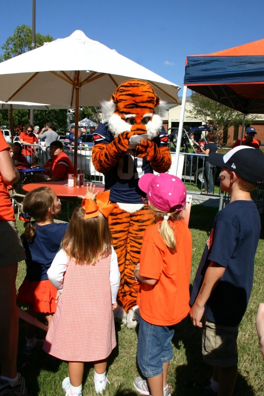 s and adults gathered around the tiger mascot