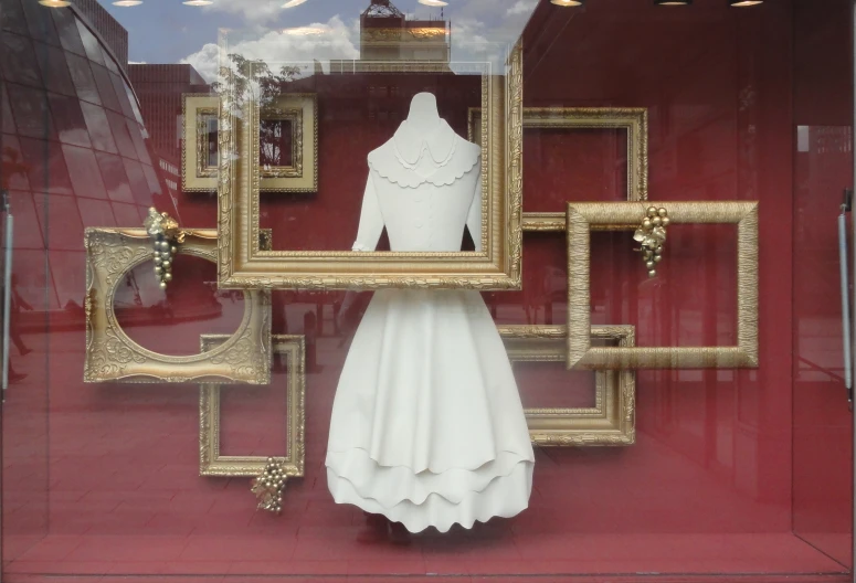 a dress and a dressmaker's mannequin inside a store window