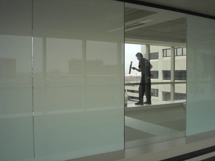 man in construction uniform standing behind a glass wall with city background