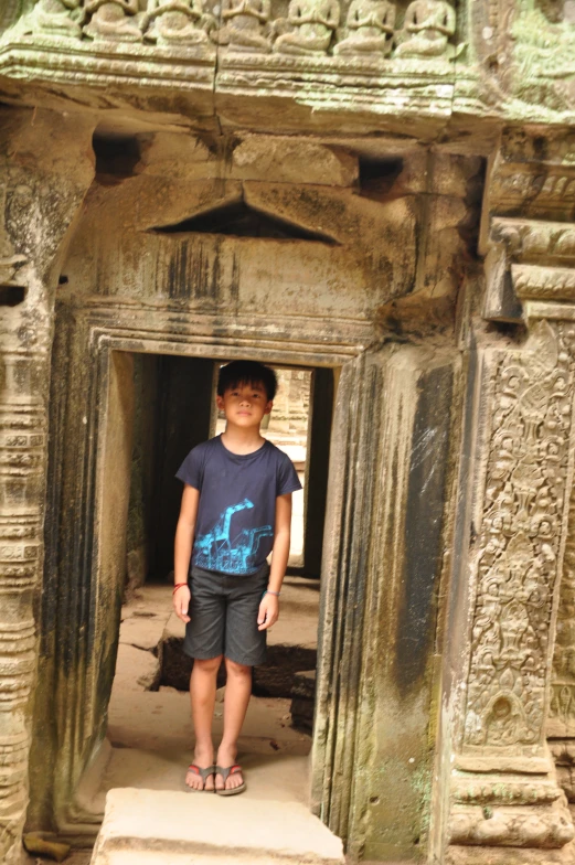 a little boy is standing by an old arch