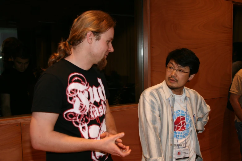 two men standing in a room talking and gesturing