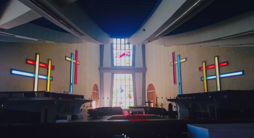 an empty church with the alter lit by stained glass windows