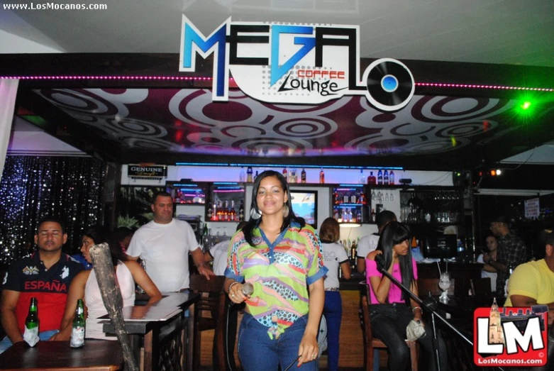 a woman in a bright shirt standing at the front of a bar