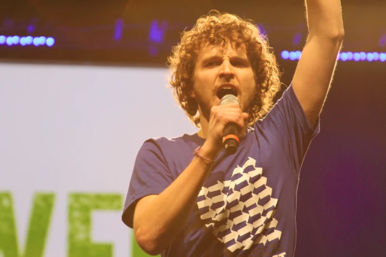 a young man with curly hair holding up a microphone