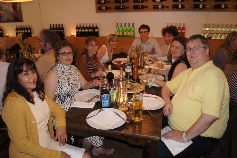 a group of people smile around a table with wine