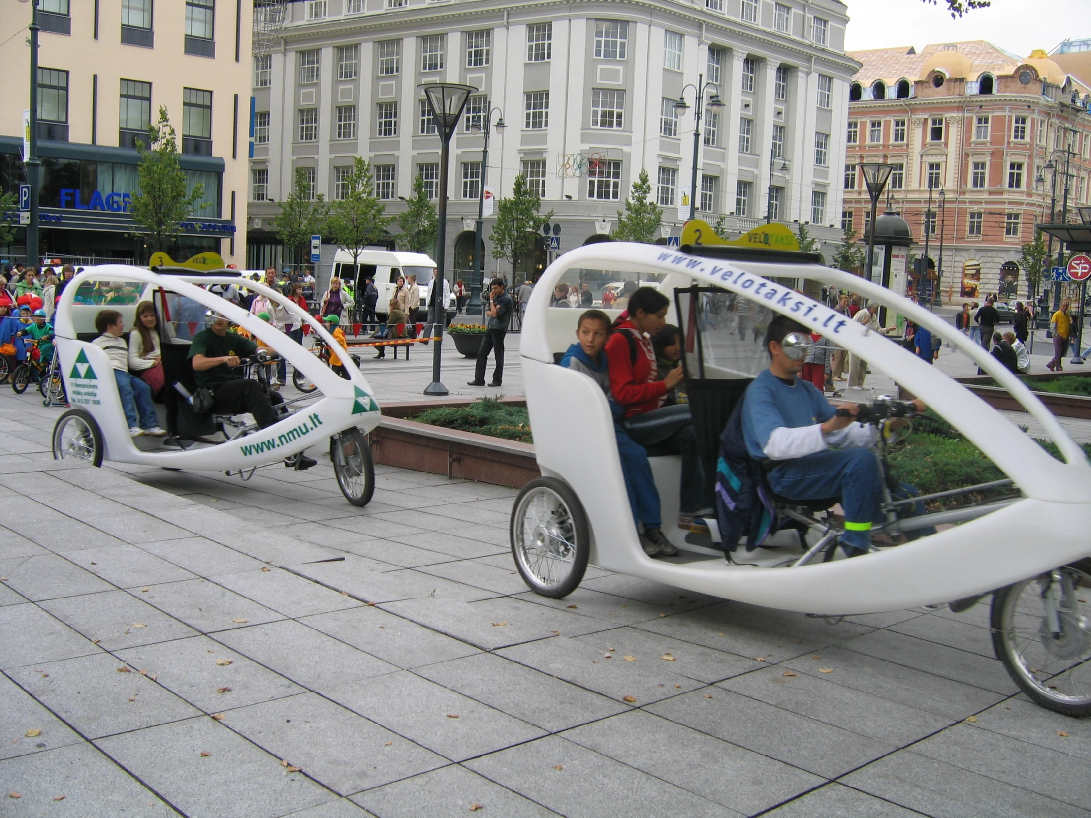 a group of people riding a vehicle next to a sidewalk