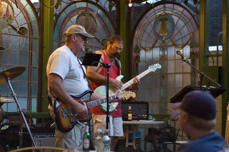 three men, each one playing a guitar and another with a microphone