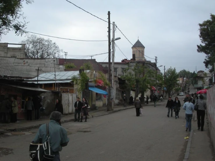 people are walking down a street next to the old buildings