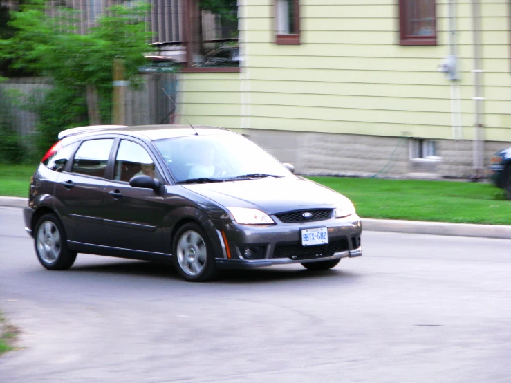 a small black ford focus driving down a road