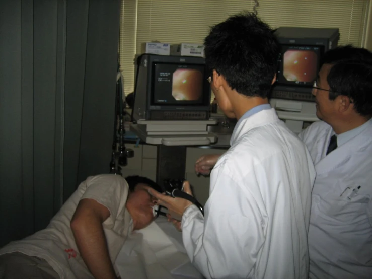 three doctors are watching the procedure that results on a patient