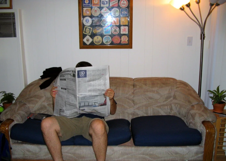 a man sitting on a couch holding up a paper