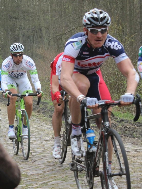 several cyclists ride through the woods on dirt