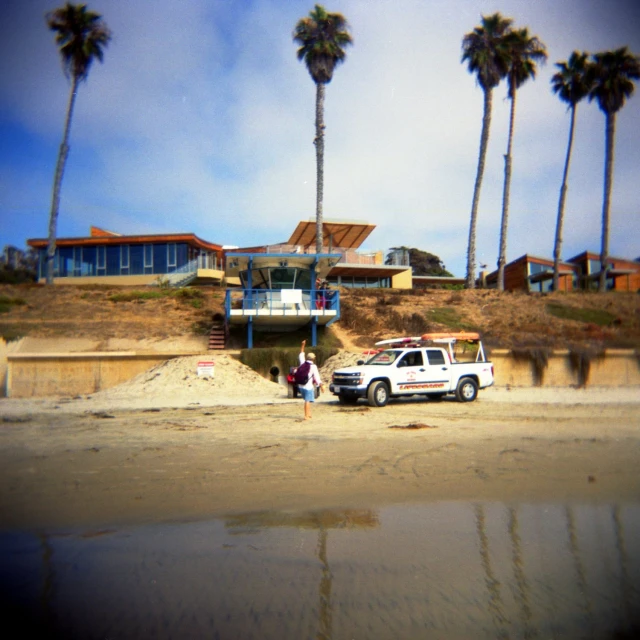 two people sitting by the side of a road with a white truck