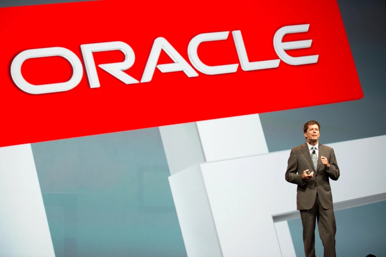 a man standing in front of a oracle sign