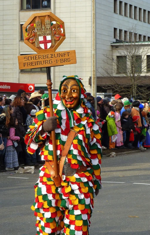 the face painted african american man poses in front of a large crowd of people