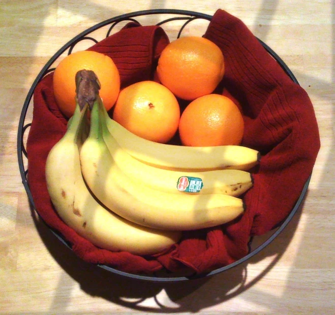 some bananas and oranges in a bowl on the table