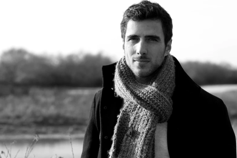 a man with a scarf stands in a black and white po