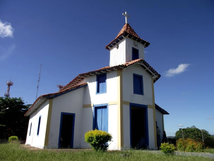 a small church with red tile roofing and blue windows