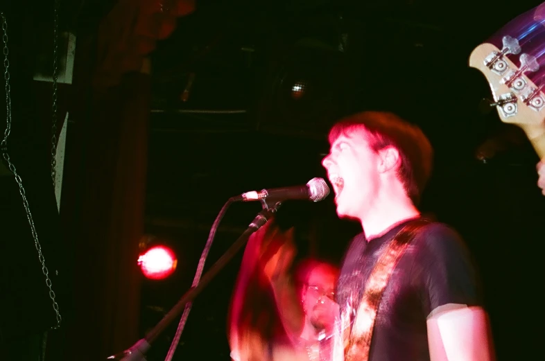 a man with an electric guitar sings into the microphone