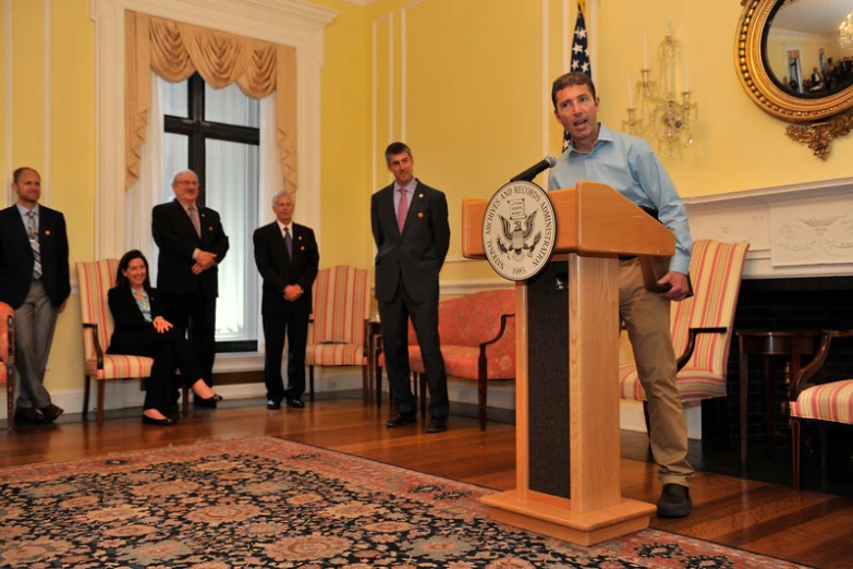 a man at a podium speaking on a carpet