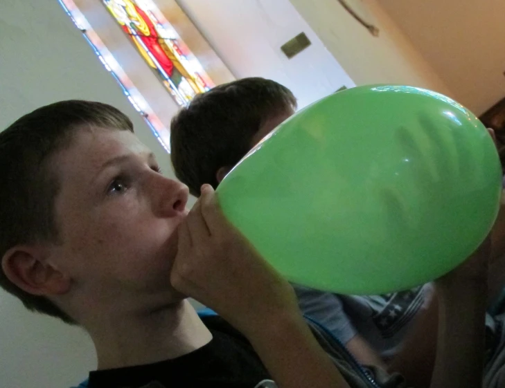 a little boy holding a green disc and chewing on it