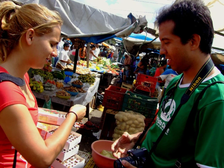 a man and woman standing next to each other looking at a bowl