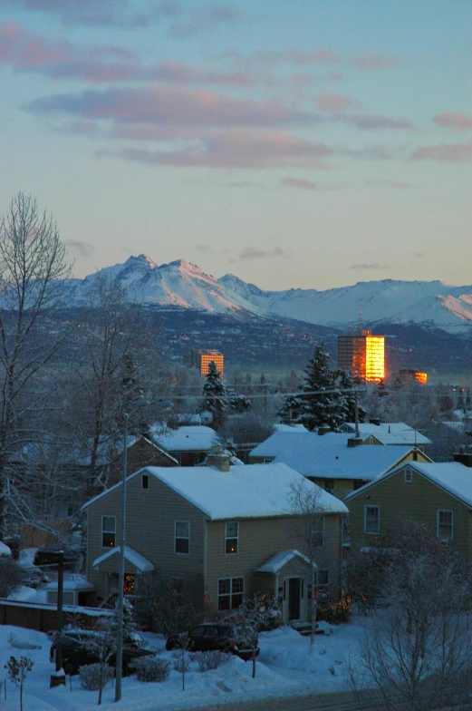 the skyline of city sits in front of mountains and is snow covered