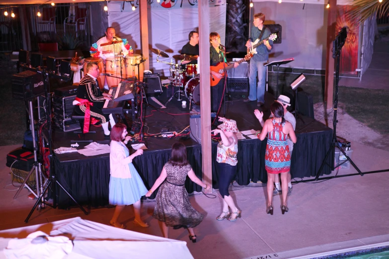 a group of people dance on stage in a tent