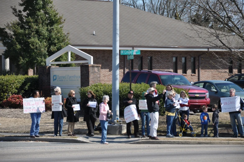 protesters stand in the street holding signs and a bicycle