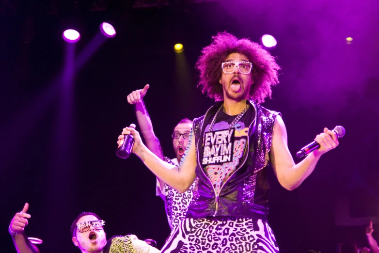 a man with pink hair wearing sunglasses, on stage