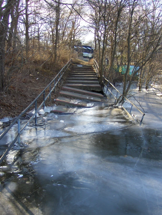 a small frozen creek with a rail way leading to steps