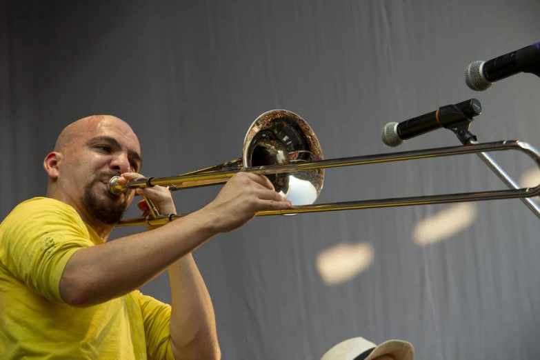a man plays the trombone on stage with microphones in front