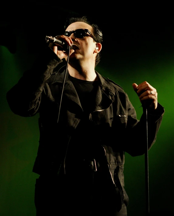 a man with sunglasses is singing into the microphone