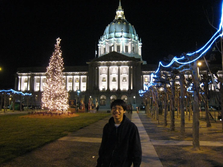 a man standing in front of a building with christmas lights