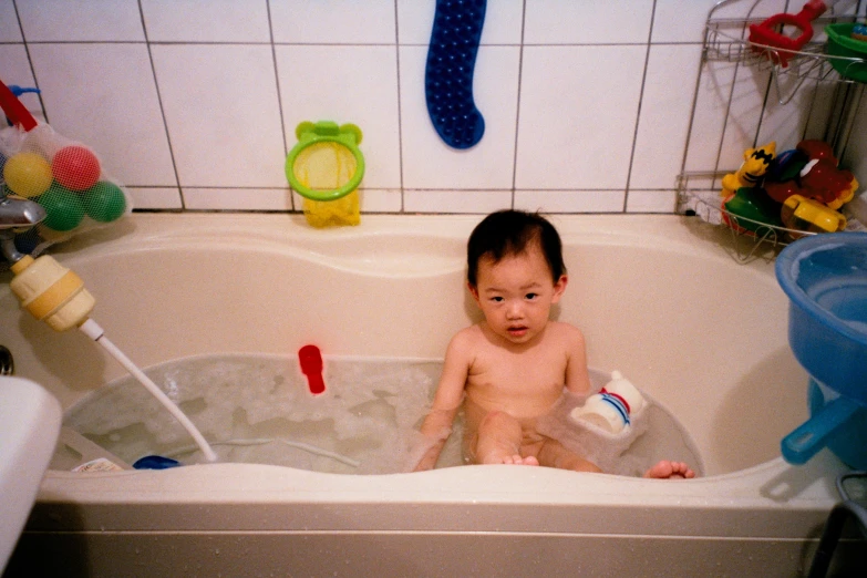 a baby sitting in a bath tub next to toys