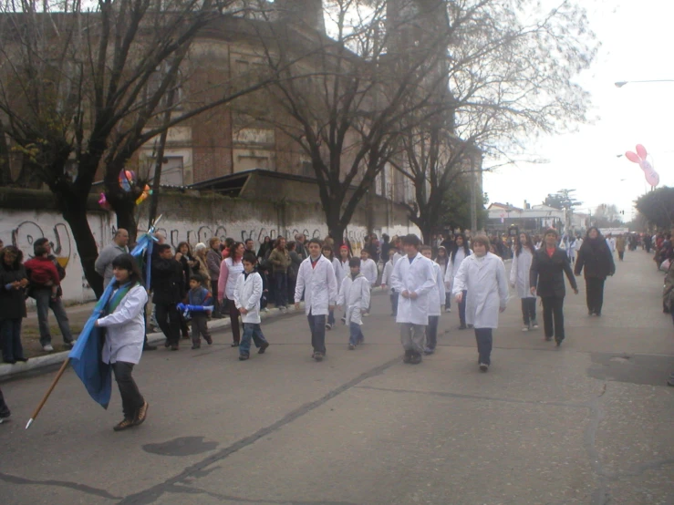 a group of medical students walking down the street in front of a crowd of people