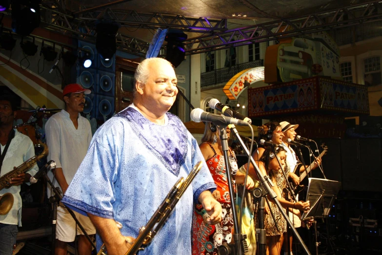 a man in a blue shirt and black hat is talking into microphones