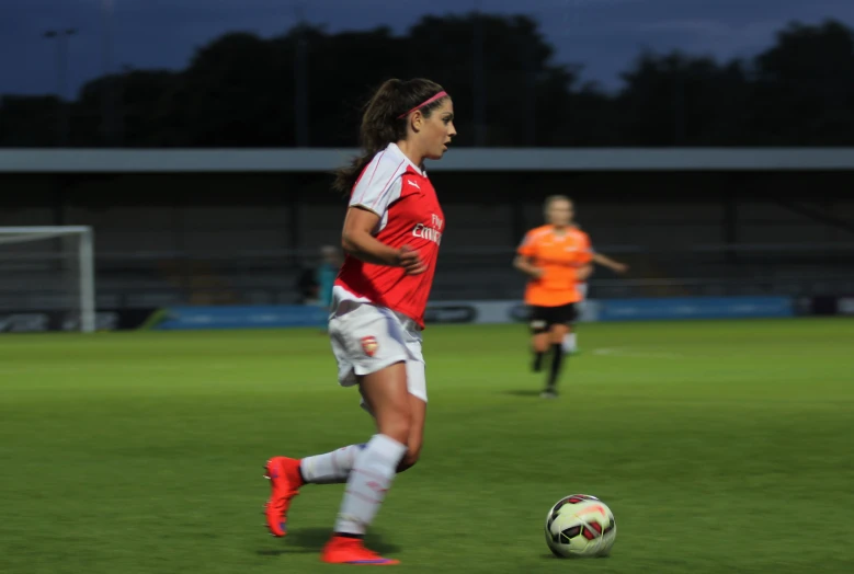 a woman standing on a field next to a soccer ball