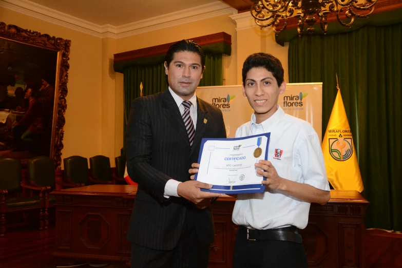 two men in business attire hold a framed award