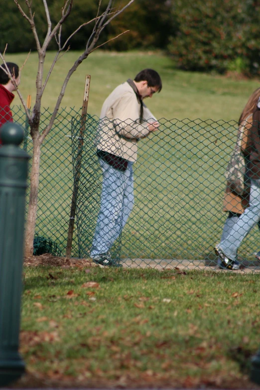 there are two men walking past a fence and talking