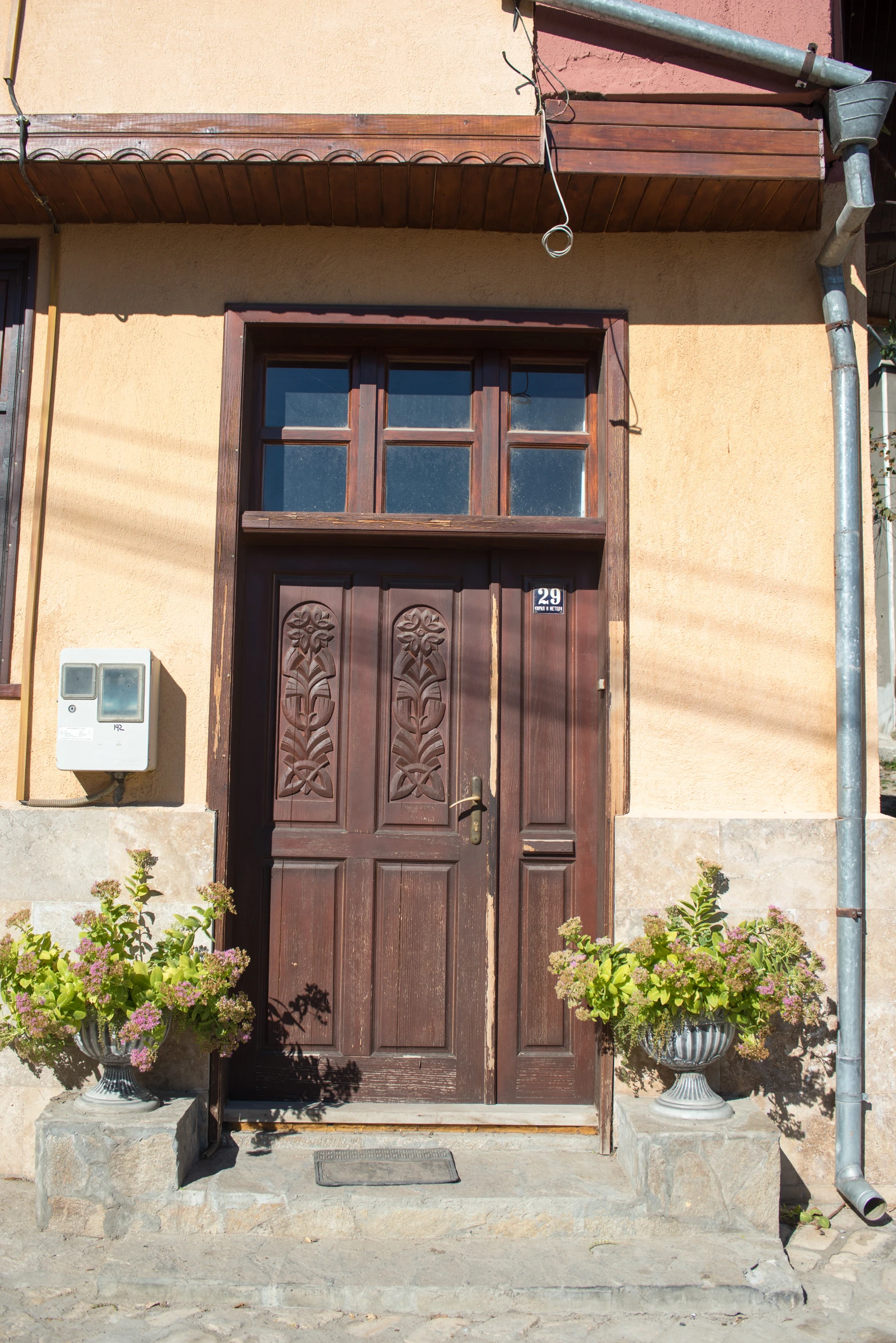 a house with large wooden doors and flower pots outside