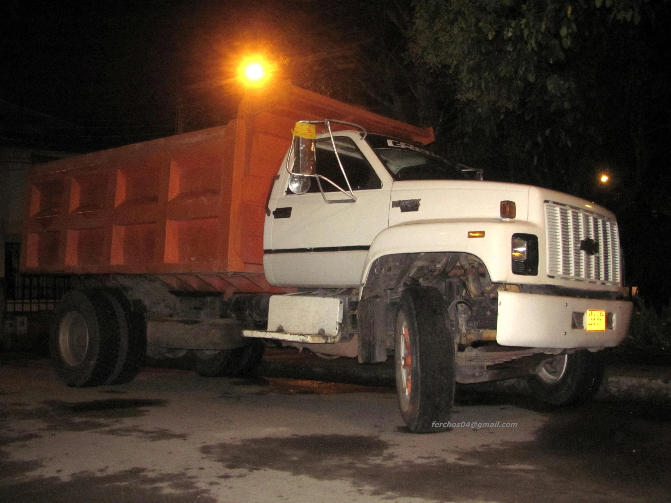 an old dump truck sits parked at night