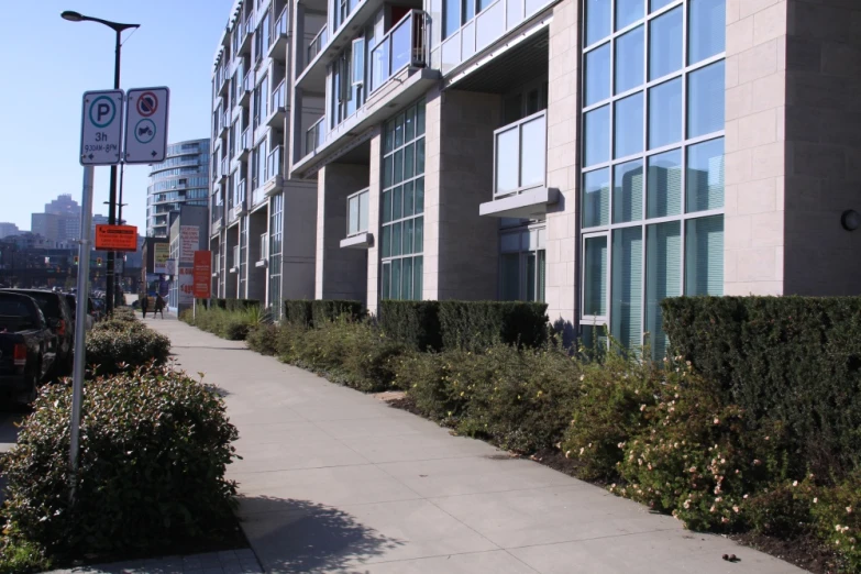 the building is grey in color and is on one side of the sidewalk