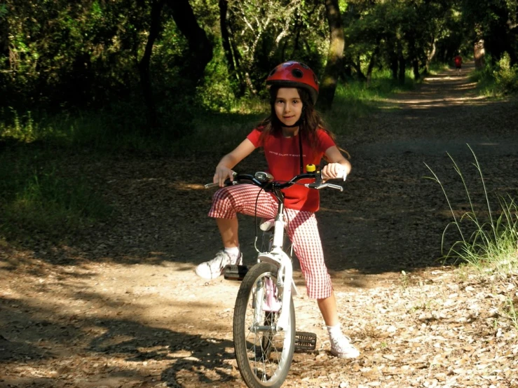 a little girl riding a bike down a dirt road