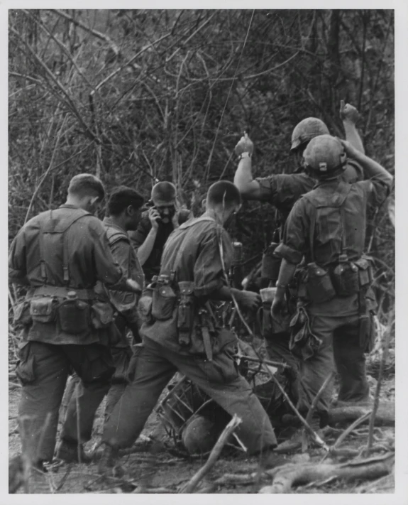 several men in uniform are in the woods and pointing